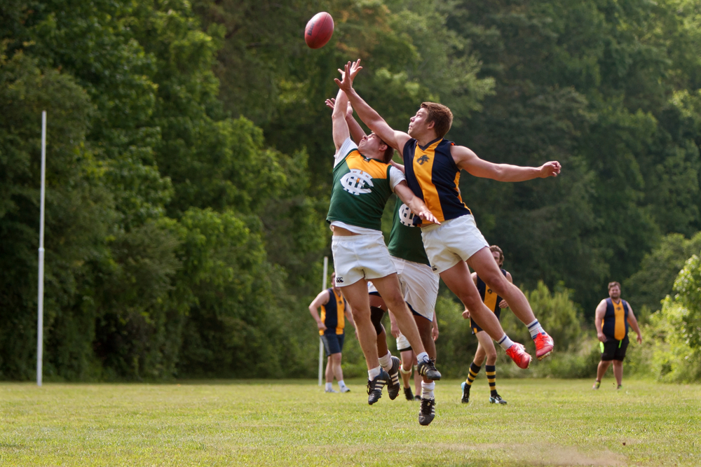 Roswell, GA, USA - May 17, 2014: Players jump and compete for the ball in an amateur club game of Australian Rules Football in a Roswell city park.